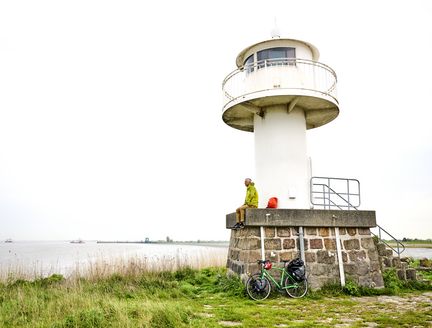 Mann sitzt auf kleinem Leuchtturm und macht eine Pause.